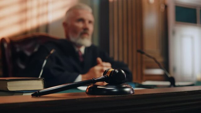 Cinematic Court of Law and Justice Trial: Honorable Male Judge Discussing Pleaded Case, Decision Guilty or Innocent Verdict after Hearing Arguments. Cinematic Blurred Shot with Focus on Gavel