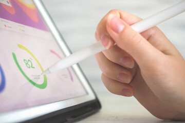 Worker analyzing financial results and company perfomance on digital tablet using wireless stylus...