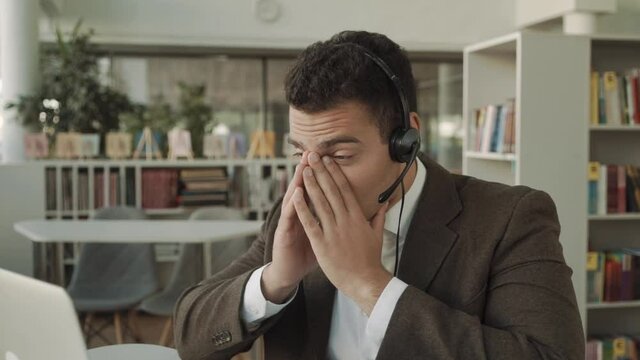 tired s man with headset near laptop in office, employee tired and burned out