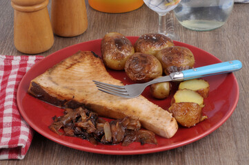 Steak d'espadon cuit avec des pommes de terre à la fleur de sel avec des oignons confits servi...