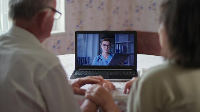medical care, back view of aged couple looking at screen of laptop and talking to doctor using video call