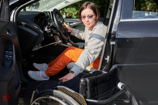 Young Disabled Person Getting Out From The Wheelchair In Her Car