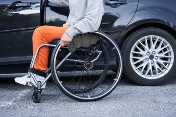 Young girl with lower body disability switches position from the wheelchair into the car