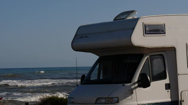 Santa Pola, Valencia, Spain - December 6, 2019: Autocaravan camping on sea shore. Sea waves moving in slow motion. Spain, Costa Blanca.