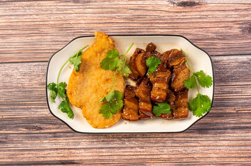 The braised meat and vegetables on the plate are on the wooden table