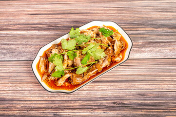 The cooked spicy chicken on a plate is on the wooden table