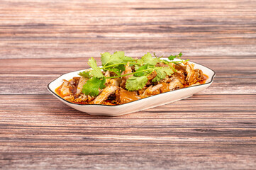 The cooked spicy chicken on a plate is on the wooden table