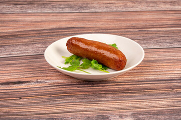 The sausage on the plate is on the wooden table
