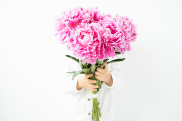 child blonde boy with big bouquet of pink peonies on white background. Love and romantic concept