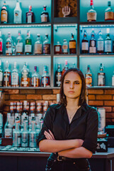 Portrait of young attractive woman bartender behind the bar counter