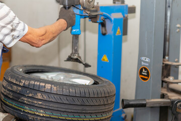 Mechanic changing tire in car service. Tire rotation machine.Car mechanic mounts tire on wheel in a workshop.