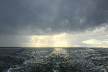 Open North Sea with Dramatic Sky after a Rain Storm. Dark Clouds and Rays of Sunshine. Filmed from the back of a boat.