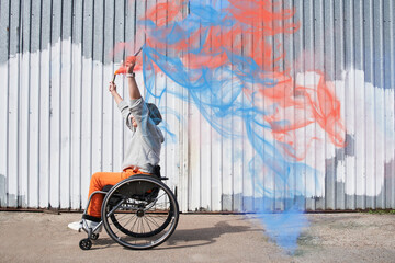 Girl with loss of leg function sitting at the wheelchair and raising her hands