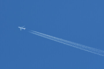 A jet forming contrails in a blue sky.