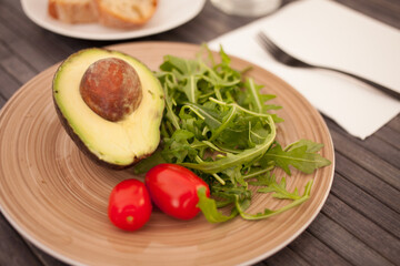 half an avocado, arugula and cherry tomatoes on plate