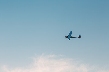 Fototapeta na wymiar Small single engine airplane flying against sunset sky.