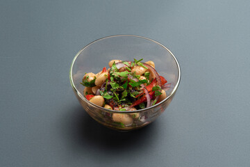 georgian lobio or salad with beans, onion, bell pepper and greens in glass bowl