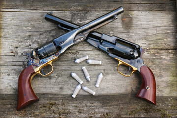 Black powder revolvers and cartridges on an old board. - obrazy, fototapety, plakaty