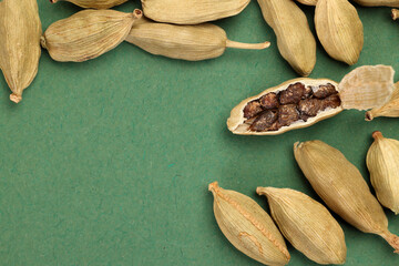 Cardamom fragrant spice seed closeup macro on green paper background