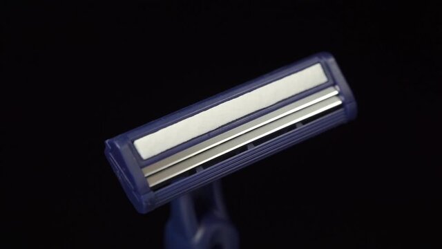 New disposable razor blade on black background. Macro shooting. Rotation