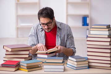 Young male student and too many books in the classroom