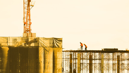 Construction of new residential high-rise buildings. Against the background of sunset sky. Working at height, Worker as in construction. technician and mechanic working on scaffolding or high crane. © Montri