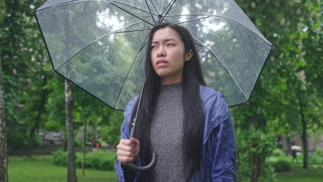 Frustrated asian woman feeling headache standing in rain, weather-related pain