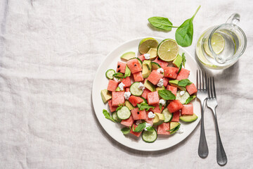 Watermelon salad with avocado, cucumber, feta cheese and arugula. Summer fruit salad. Top view,...