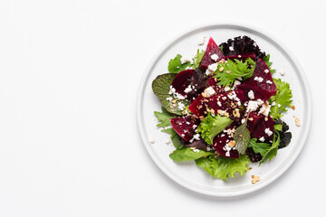 Beetroot salad with feta cheese and walnuts. Vegetable salad in plate on white background, top view