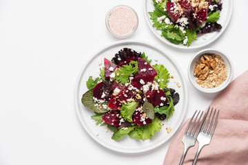 Beetroot salad with feta cheese and walnuts. Vegetable salad in plate on white background, top view