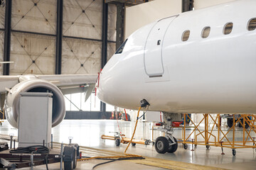 Modern new white passenger airplane on maintenance repair check in airport hangar indoors. Aircraft. Plane, shipping, transportation concept