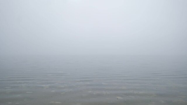 Video of a lake in fog, small waves rush to the shore