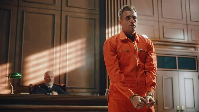 Court of Law and Justice Trial Proceedings: Portrait of Accused Male Criminal in Orange Jumpsuit Giving Testimony to Judge, Jury. Speech of Law Offender Denying Charges, Pleading, Asking for Pardon.