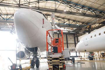 Modern passenger airplane on maintenance repair check in airport hangar indoors. Aircraft. Plane, shipping, transportation concept