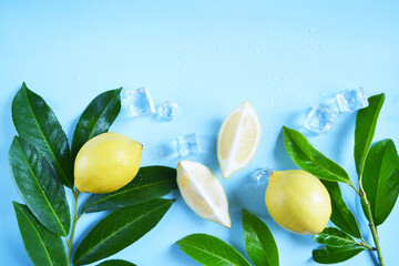 Frame, lay out ice cubes, lemons with green leaves and water drops on the blue background. Summer vibes. Cooling fresh humid template composition. Empty space for text on the top. Flyer, card.