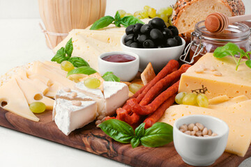 Cheese platter with assorted cheese, sausage, jam, black olives, pine nuts and grapes topped with basil. Appetizer variation