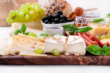 Cheese platter with assorted cheese, sausage, jam, black olives, pine nuts and grapes topped with basil. Appetizer variation