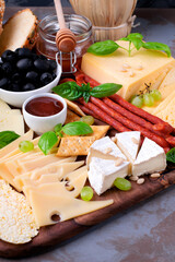 Cheese platter with assorted cheese, sausage, jam, black olives, pine nuts and grapes topped with basil. Appetizer variation