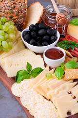 Cheese platter with assorted cheese, sausage, jam, black olives, pine nuts and grapes topped with basil. Appetizer variation