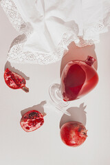 Pomegranates with a vase on pastel background with white cloth and sunlit. Top view. Flat lay