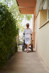 Fototapeta na wymiar Unrecognizable walking her 90 year old mother on wheelchair