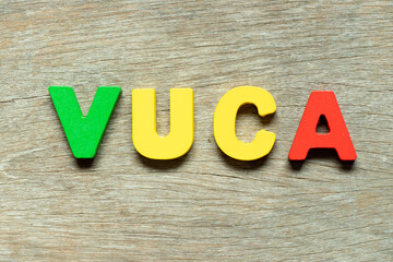 Color alphabet letter in word VUCA (abbreviation of Volatility, uncertainty, complexity and ambiguity) on wood background