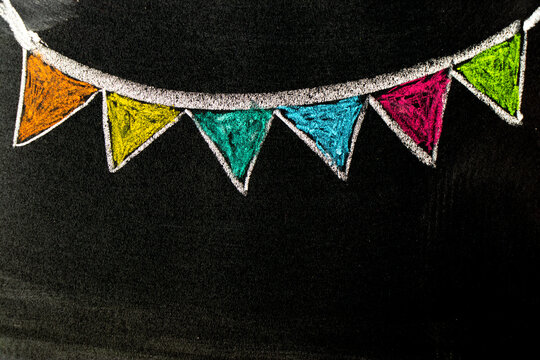 Colorful chalk handdrawing in hanging party flag shape on blackboard or chalkboard background with copy space