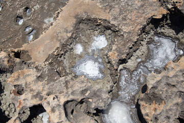 the sea coast in the form of bottom sediments flooded with seawater with the formation of salt patterns and sea lagoons in the form of textures and stone abstractions under water with shadows from the