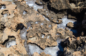 the sea coast in the form of bottom sediments flooded with seawater with the formation of salt patterns and sea lagoons in the form of textures and stone abstractions under water with shadows from the