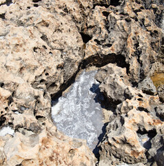 the sea coast in the form of bottom sediments flooded with seawater with the formation of salt patterns and sea lagoons in the form of textures and stone abstractions under water with shadows from the