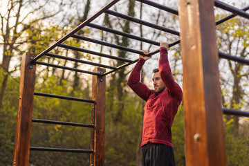 Obraz premium Man doing pull ups while doing an outdoor workout