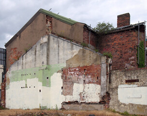 an abandoned derelict old house with crumbling brick walls propped up with scaffolding and...
