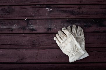dirty gloves, leather work gloves with dirt on them. wooden background
