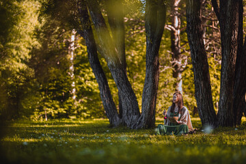 yogi woman sitting in the forest and playing music bowls